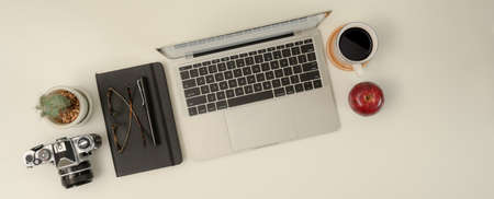 Top view of modern workspace with laptop, stationery, camera and supplies on white tableの写真素材