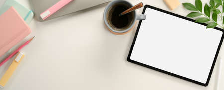 Top view of feminine study table with mock up tablet, laptop, stationery, coffee cup, decoration and copy space on deskの写真素材