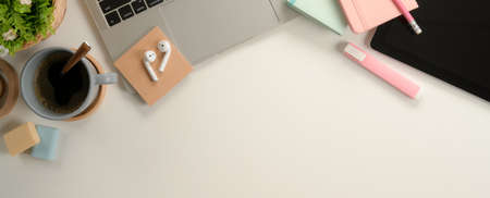 Top view of feminine study table with laptop, tablet, stationery, coffee cup and copy space on white...