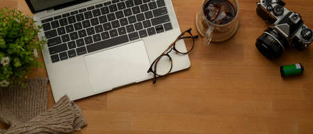 Overhead shot of workspace with laptop, camera, glasses, coffee cup, decoration and copy pace on...
