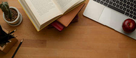 Top view of study table with copy space, laptop, books, stationery and decorations on wooden table