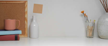 Close up view of workspace with copy space, painting brushes, books and decorations on white tableの写真素材