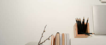 Top view of study desk with copy space, laptop, stationery and books on white table