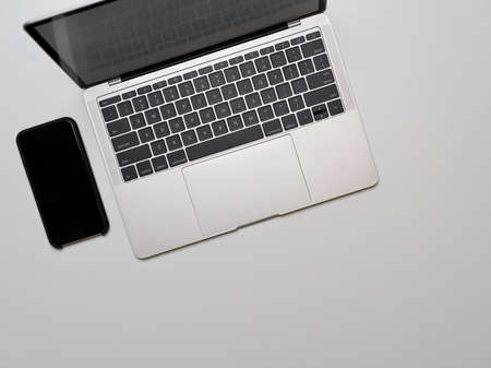 Top view of portable workspace with computer laptop and smartphone on white deskの写真素材