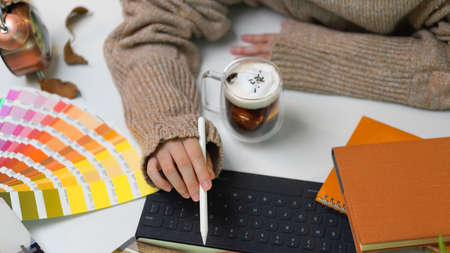 Cropped shot of female holding stylus pen and pointing on digital tablet screen while sitting at worktableの写真素材
