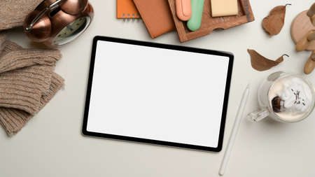 Top view of study table with digital tablet, stationery, cup of beverage and decoration on white...