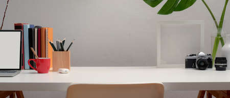 Close up view of workspace with mock up laptop, stationery, decorations, books and copy space on...