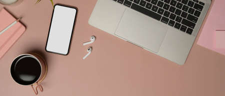 Top view of feminine worktable with smartphone, laptop, accessories, coffee cup and copy spaceの写真素材