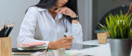 Cropped shot of female office worker using digital tablet on office desk with office supplies