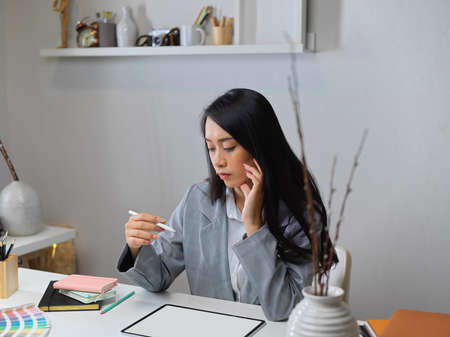 Portrait of businesswoman thinking about her project while working with mock up tablet in office roomの写真素材