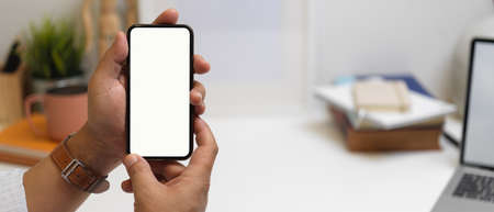 Close up view of male entrepreneur showing blank screen smartphone with blurred office background