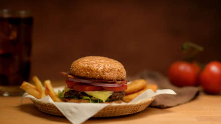 Close up view of fresh tasty grilled burger and french fries serving on wicker trayの写真素材