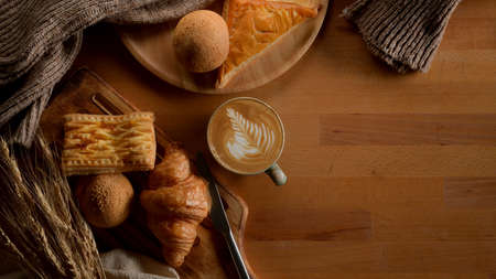 Top view of breakfast table with freshly baked bakery, latte coffee, decorations and copy space on...