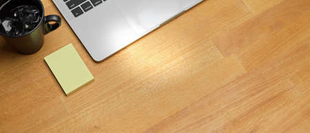 Top view of workspace with laptop, sticky note, mug and copy space on wooden table