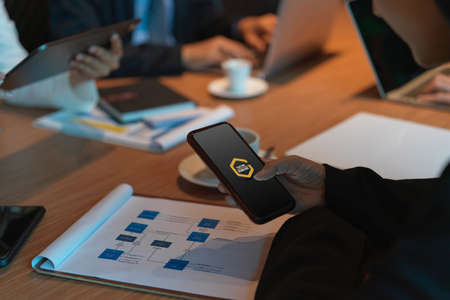 Side view of businesswoman using mock up smartphone while meeting with her colleagues in conference...
