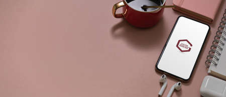 Cropped shot of pink study table with mock up smartphone, notebook, earphone, coffee cup and copy...
