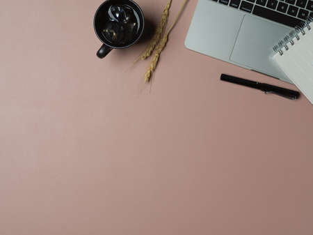 Top view of worktable with copy space, laptop, coffee mug and stationery on pink tableの写真素材