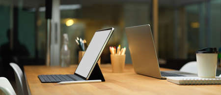 Cropped shot of laptop and digital tablet with keyboard on wooden table in meeting room, clipping path.の写真素材