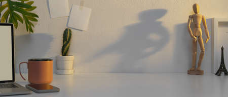 Close up view of workplace with copy space, coffee mug, mock up laptop and decorations on white tableの写真素材