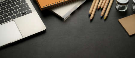 Cropped shot of workspace with laptop, stationery, supplies and copy space on black leather tableの写真素材