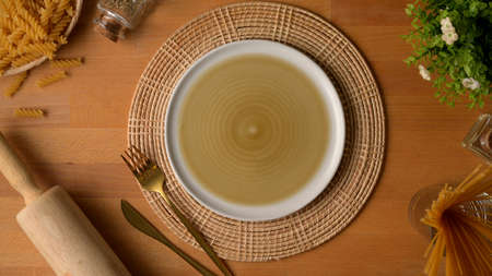 Top view of dinning table with mock up plate, silverware on placemat, ingredients and kitchen tools...