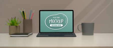 Close up view of study table with mock up digital tablet, stationery, mug and plant pot on white...