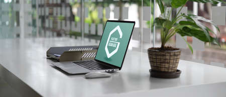 Side view of office desk with mock up laptop, office paper filing trays and plant pot decorated in office roomの写真素材