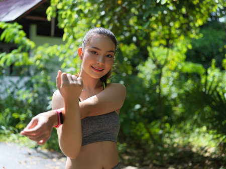 Portrait of a woman in sportswear stretching her arm to cool down after morning exercises in nature