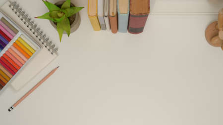 Top view of study table with copy space, books, plant pot, stationery and oil pastelsの写真素材