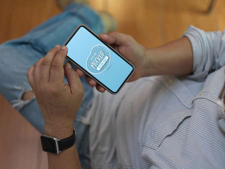 Top view of male worker using mock up smartphone while relaxed sitting on office chair