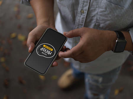 Cropped shot of male using mock up smartphone while standing on street