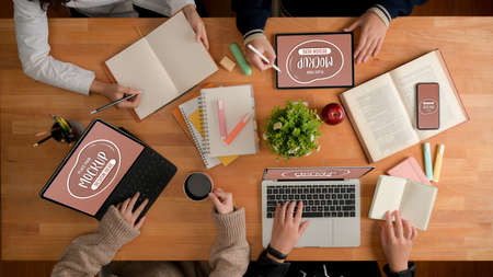 Overhead shot of university students doing group assignment with mock up digital devices, books and stationeryの写真素材