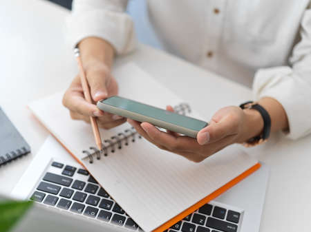 Close-up view of young businessman looking at his smartphone while working in office room