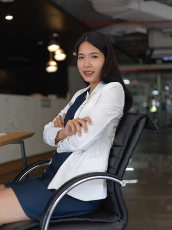 Portrait of young pretty businesswoman smiling to the camera while sitting in office roomの写真素材