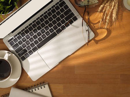 Top view of comfortable working table with laptop computer and coffee cup with copy space and office...