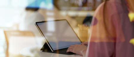 Cropped shot of young collage student working on her project with tablet, view through glass view