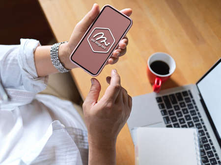Cropped shot of male worker working with mock up smartphone at worktable in office room