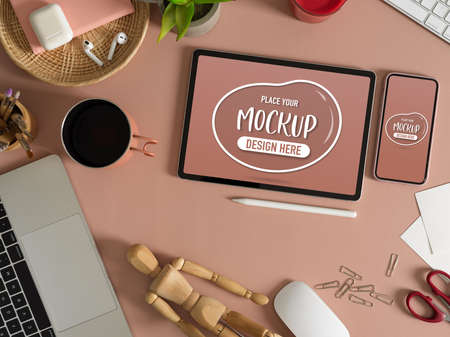 Top view of mock up tablet and smartphone on pink table with accessories and suppliesの写真素材