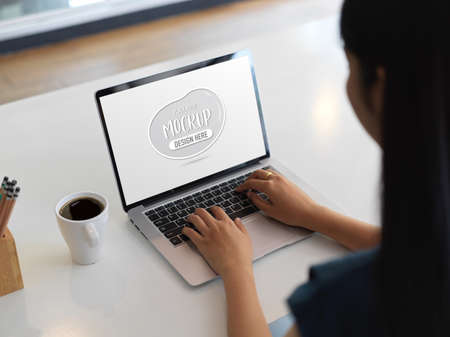 Close-up view of young woman working on her project while typing on laptop computerの写真素材
