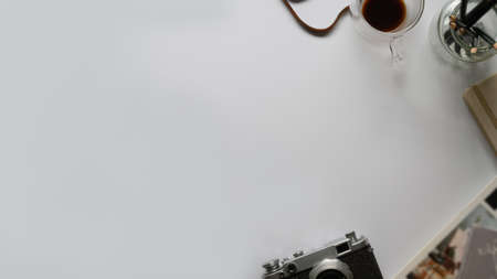 Top view of modern worktable with copy space, camera, office supplies and coffee cup