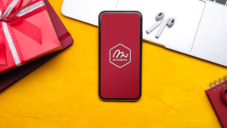 Top view of colourful home office desk with mock up smartphone, earphone, laptop and gift boxの写真素材
