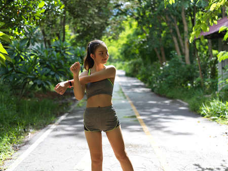 Portrait of young female athlete stretching her arm before exercise in the park