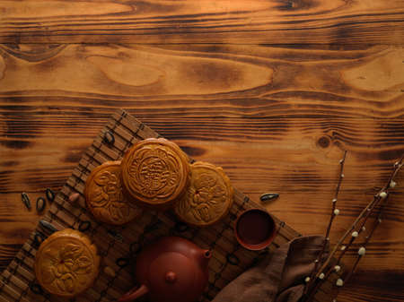 Top view of traditional moon cakes on bamboo mat with tea set and copy space on rustic table....