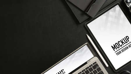 Top view of black table with mock up tablet, smartphone, notebooks and copy space