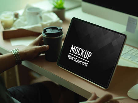 Cropped shot of male office worker using mock up digital tablet on computer deskの写真素材