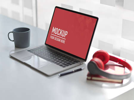 Cropped shot of workspace with mock up laptop, headphone, notebook and mug on white desk