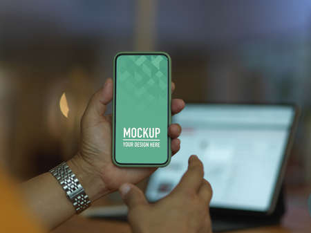 Close up view of male hand holding mock up smartphone in blurred background