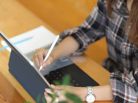 Top view of female hand using digital tablet with stylus pen on wooden tableの写真素材