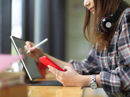 Side view of female teenager with headphone using digital tablets and smartphone in cafe