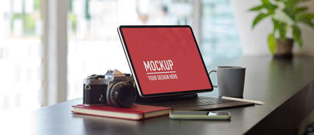 Closeup view of worktable with mock up digital tablet, camera, stationery and supplies in office...
